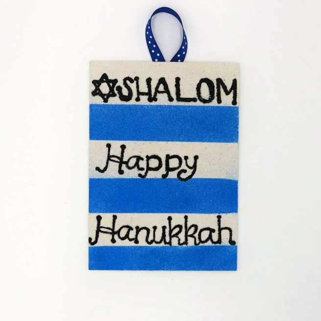 Create pretty Hanukkah wall art with colored sand and blank adhesive boards.